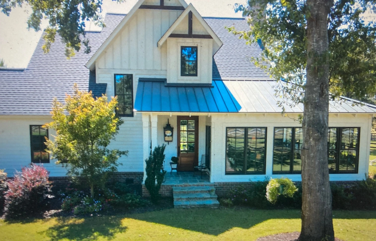 Garden entrance to the Aiken home with dark-framed windows, a covered doorway and stone steps