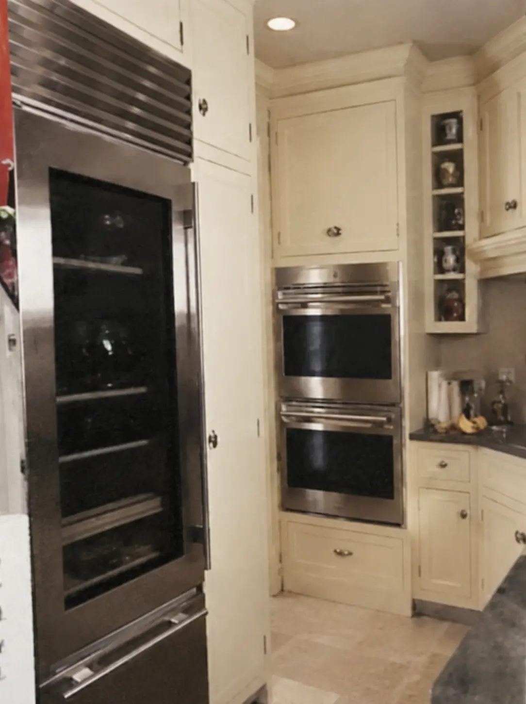 Restored archival photograph of the pantry wine refrigerator and stacked wall ovens in cream cabinetry