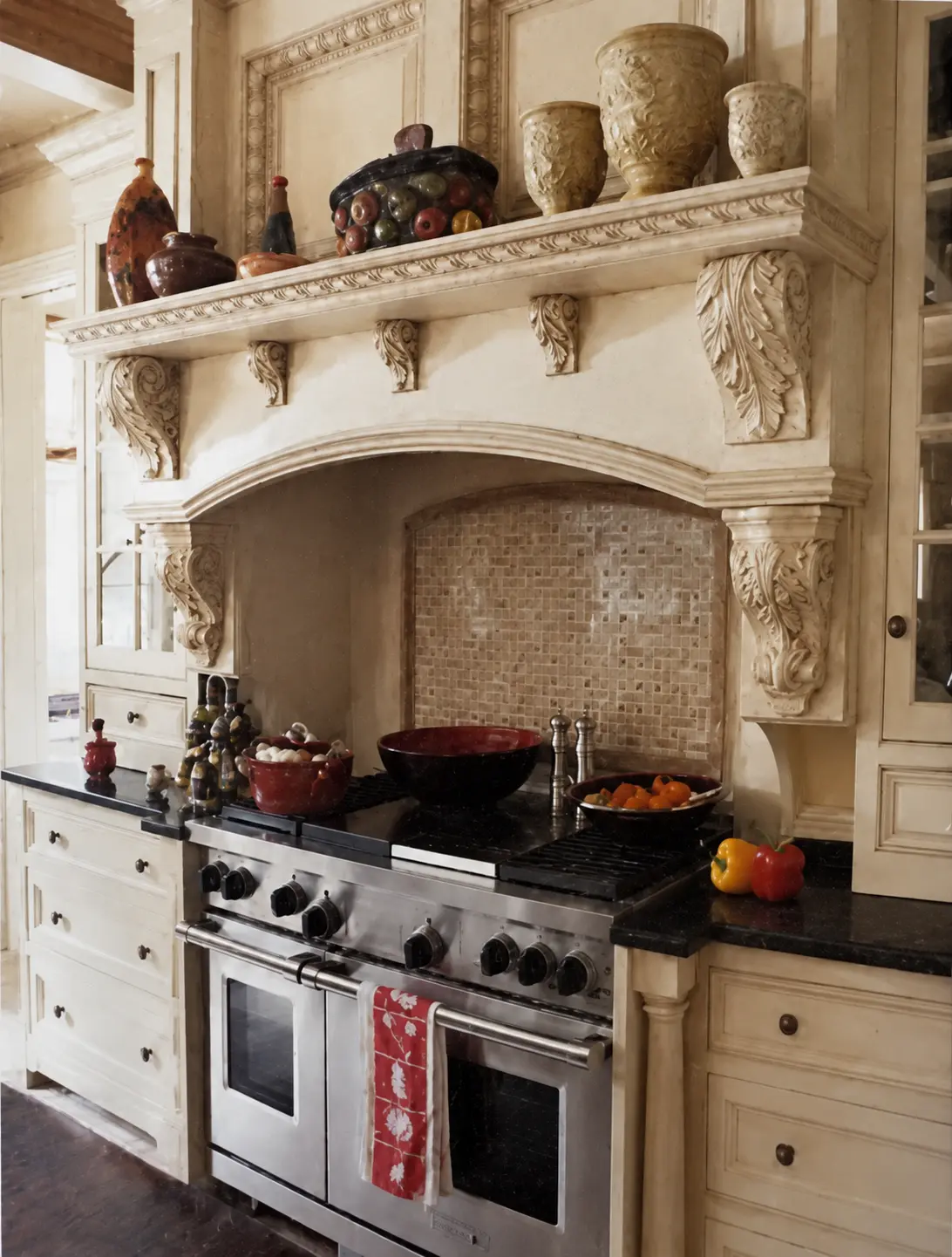 Restored archival detail of the carved cream range hood, mosaic backsplash and stainless range