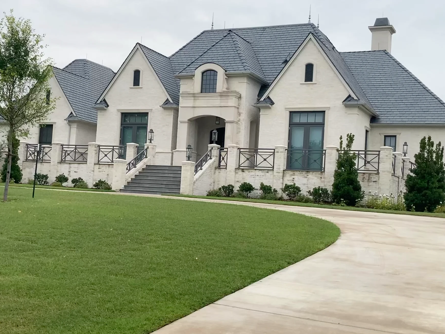 A stone residence with a slate roof, generous windows, and a terrace opening onto a sweeping lawn