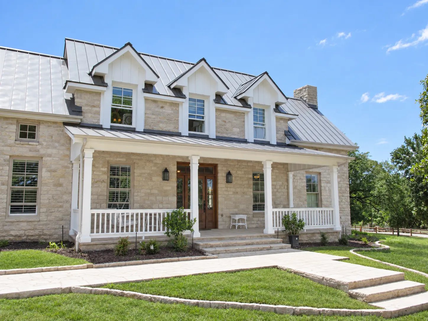 Stone farmhouse with a deep front porch and three gabled dormers