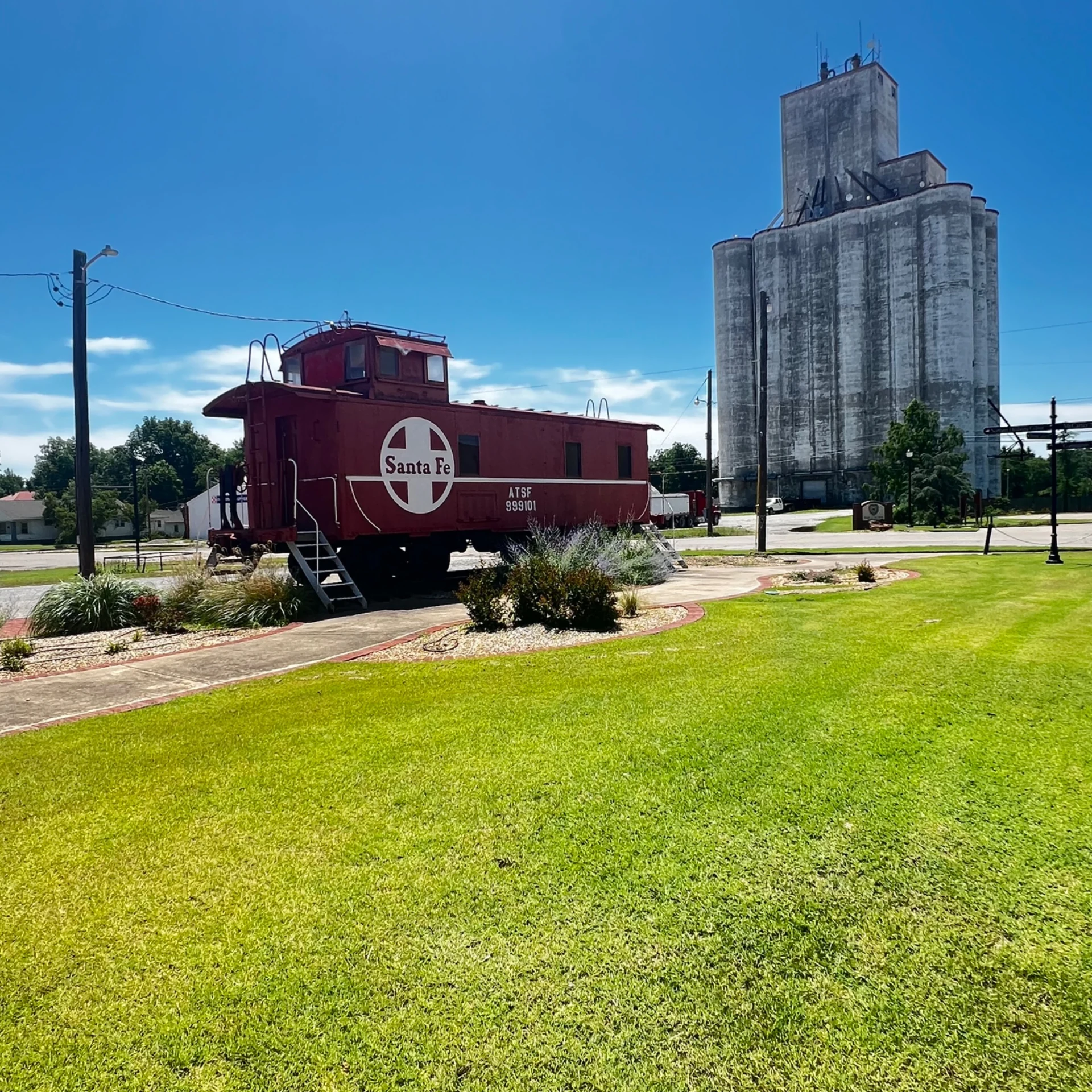 A red Santa Fe rail car beside the Tonkawa depot and historic grain elevators